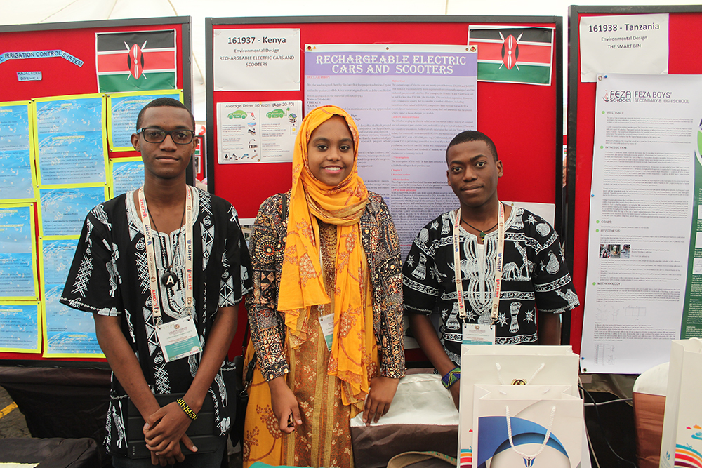 Three students standing in front of their project posters at the exhibition